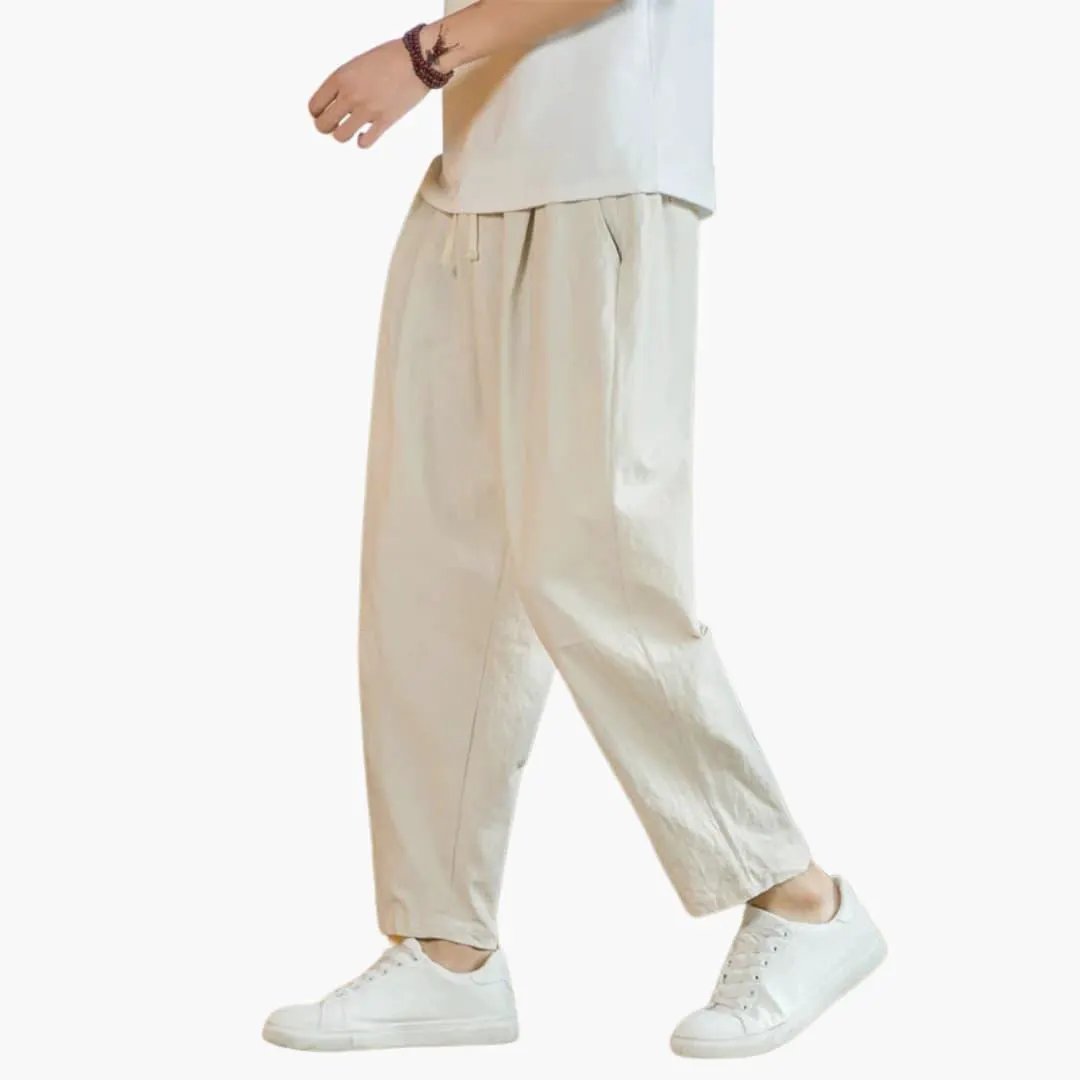Men's beige trousers with relaxed fit and drawstring waist, paired with white sneakers