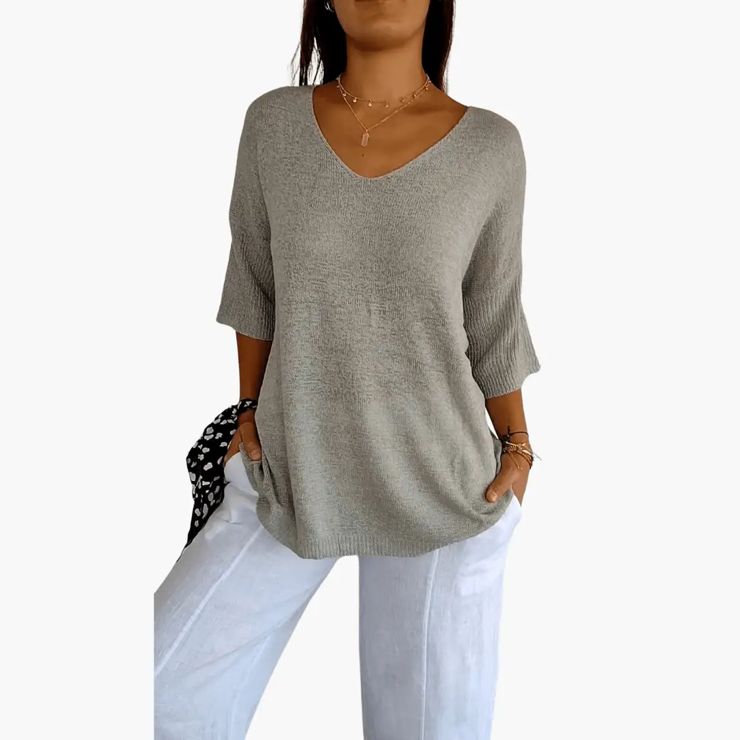 Women's V-neck loose knit top in beige with 3/4 sleeves, paired with light jeans