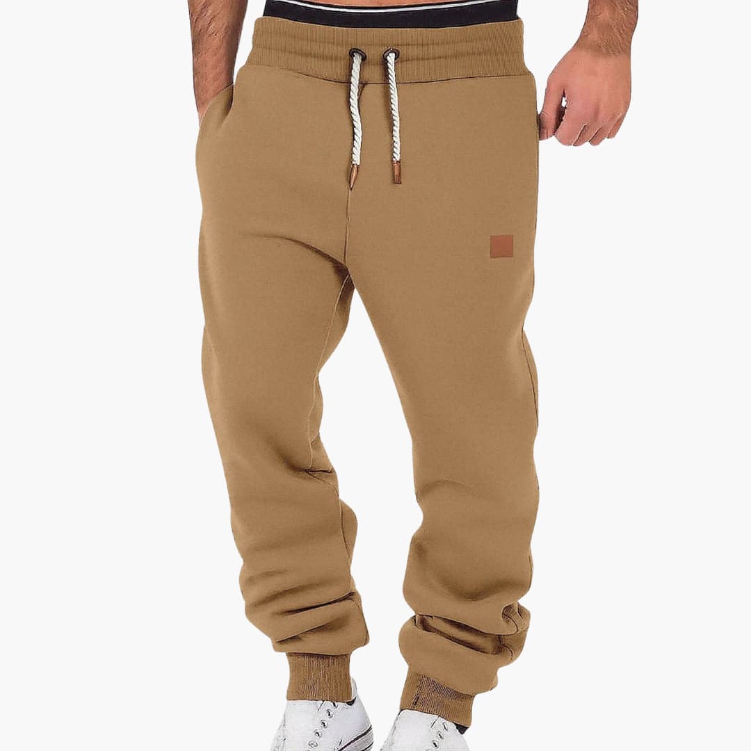 Men's jogging pants in tan with pockets and drawstring waistband, cuffed ankles, Wilfred Smith patch.