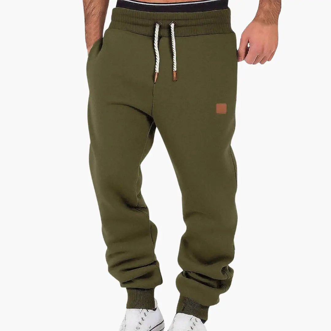 Men's jogging pants olive green with pockets and drawstring waist, logo patch on thigh.