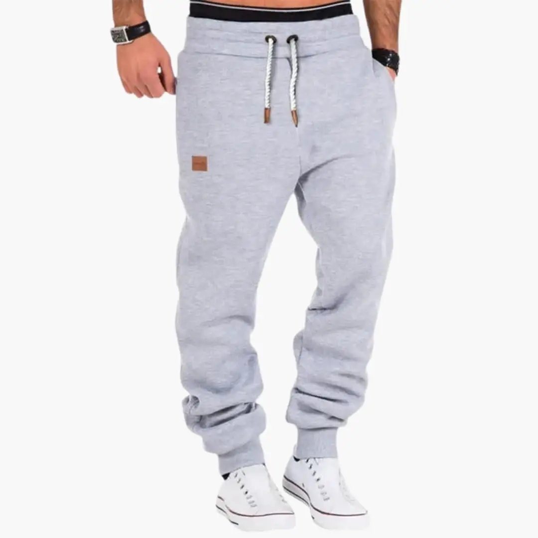 Men’s gray jogger pants with ribbed cuffs, drawstring waist, and front pockets by Wilfred Smith