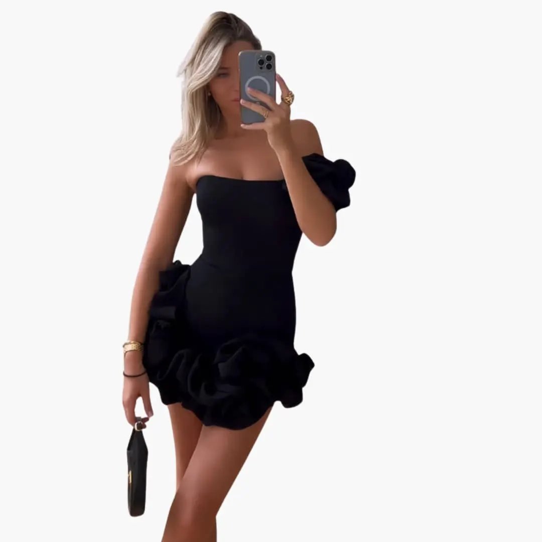 Women’s one-shoulder dress by Wilfred Smith in black with asymmetric neckline and voluminous ruffle hem.