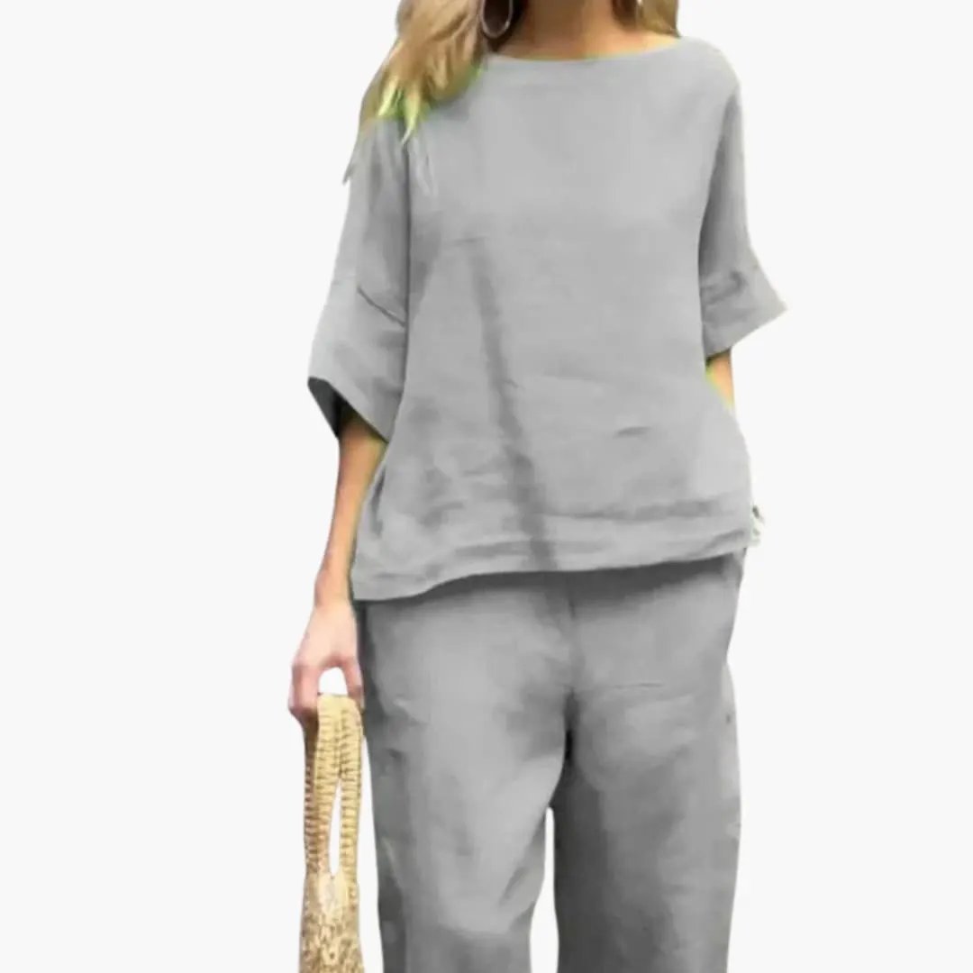Women’s two-piece gray crop top and cropped pants set; loose top with wide-leg pants, model holding a woven bag