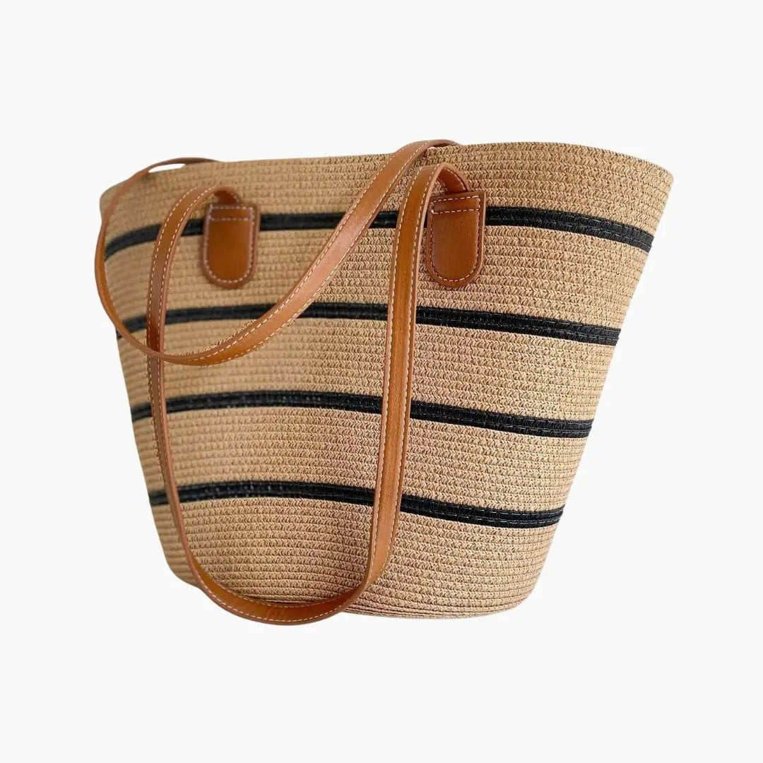Women's tote bag in natural woven straw with black stripe accents and tan leather shoulder straps.