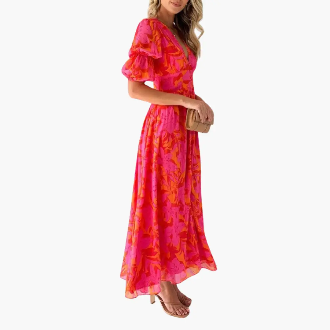 Elegant pink-orange floral maxi dress for women with V-neck and puff sleeves, paired with beige clutch and sandals.