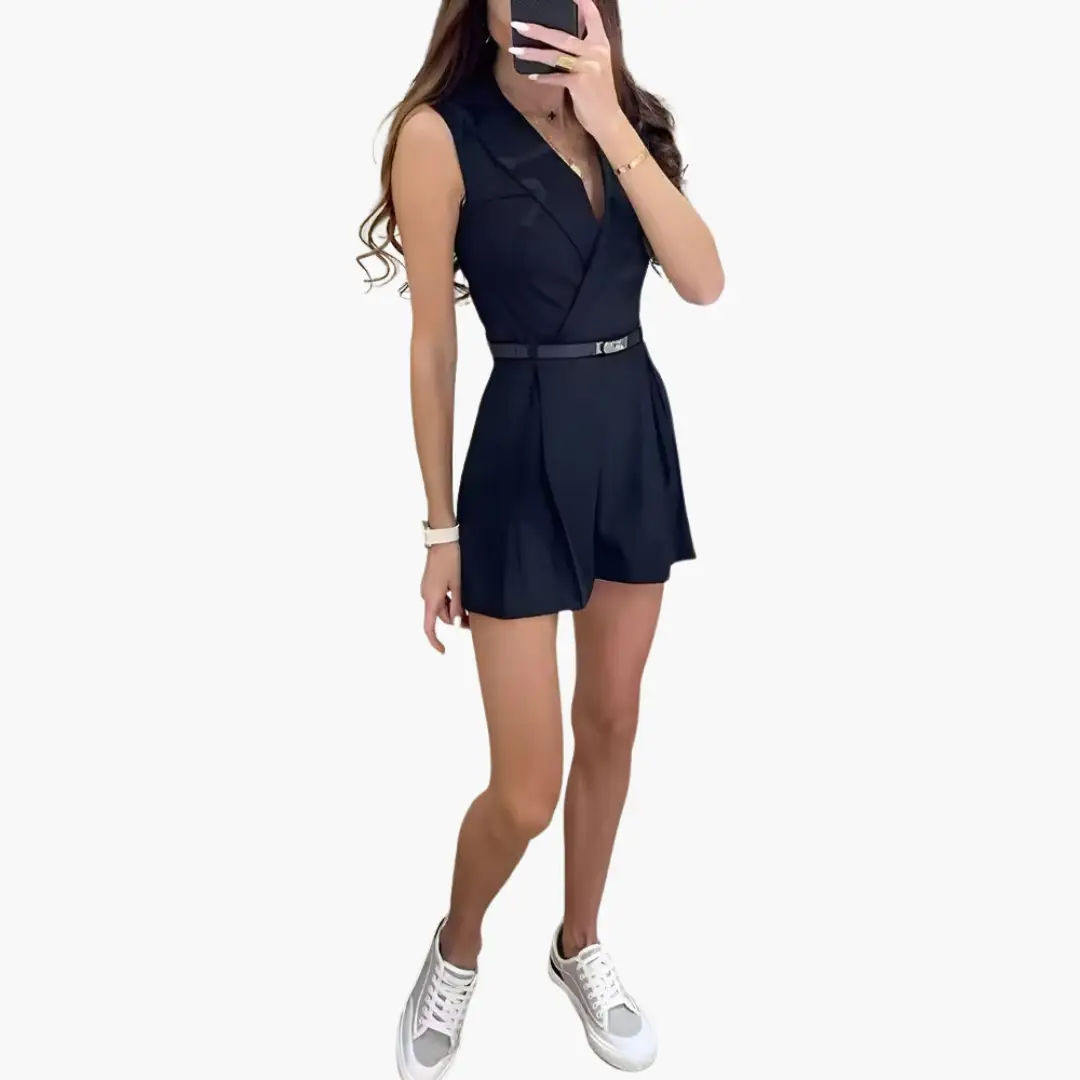 Jumpsuit, navy sleeveless with belted waist and lapel collar, short-length style, model wearing white sneakers