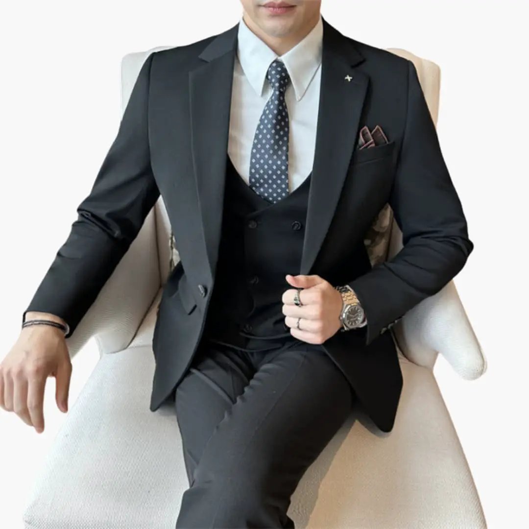 Three-piece men's suit by Wilfred Smith with notch lapel in black fabric, white shirt and blue dotted tie