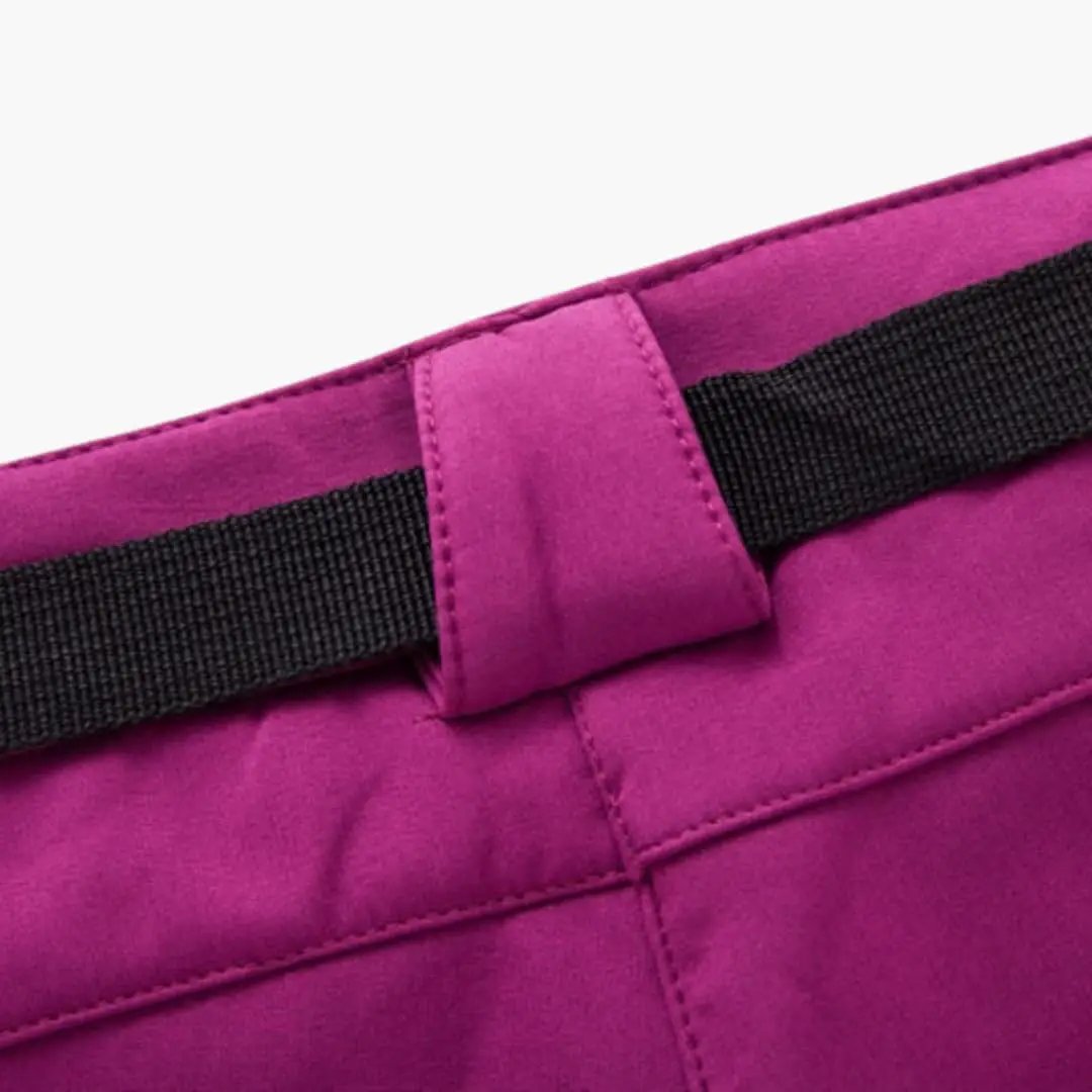 Women's hiking pants in magenta with zipper pockets and a black belt.