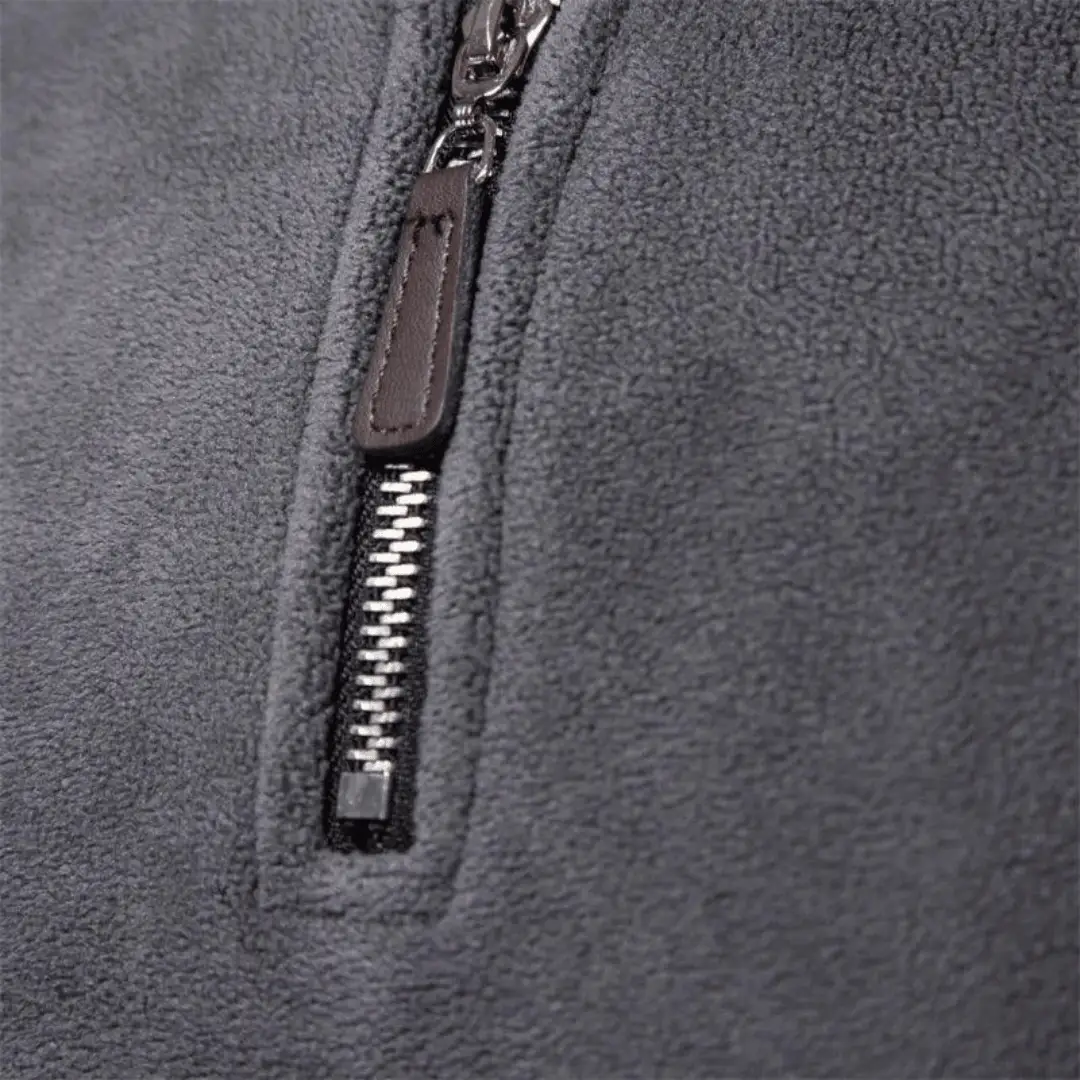 Men’s fleece pullover zipper close-up; grey fabric with metal teeth and leather pull tab