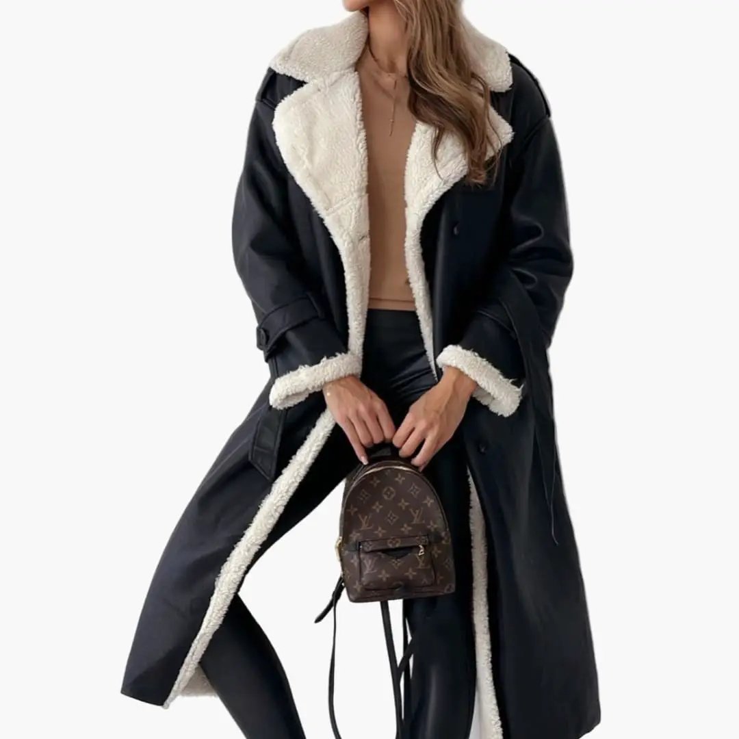 Women's long black coat with notched collar and faux fur lining, model holding Louis Vuitton mini backpack.
