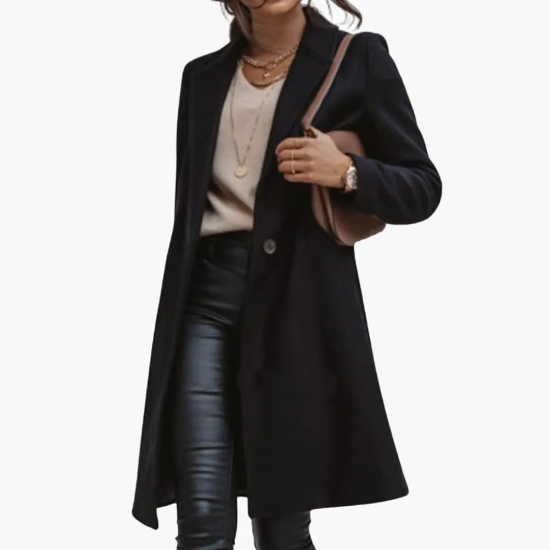 Women's long coat by Wilfred Smith in black with collar and button closure, worn over beige top.