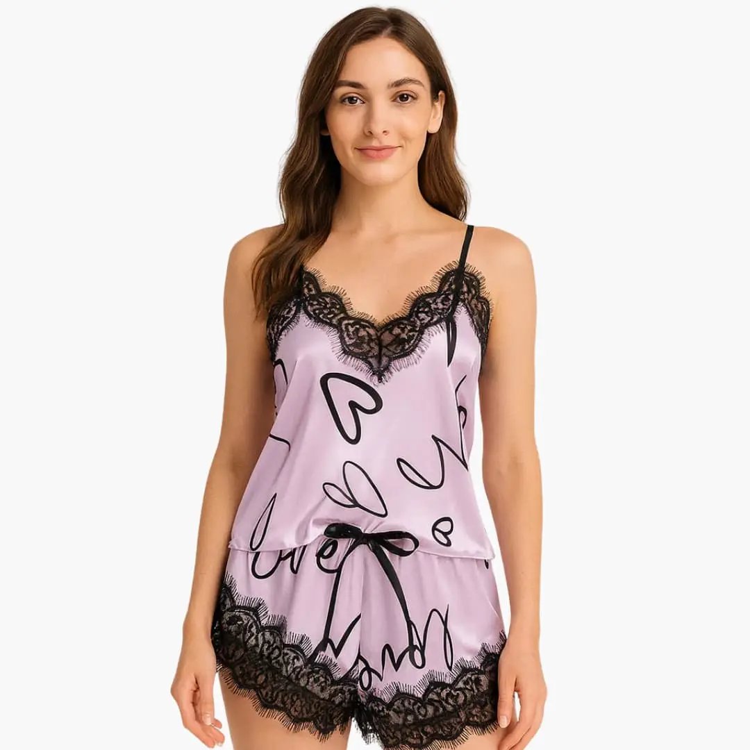 Women's lavender satin pajama set with spaghetti top and printed shorts, black lace trim, and bow at waist.