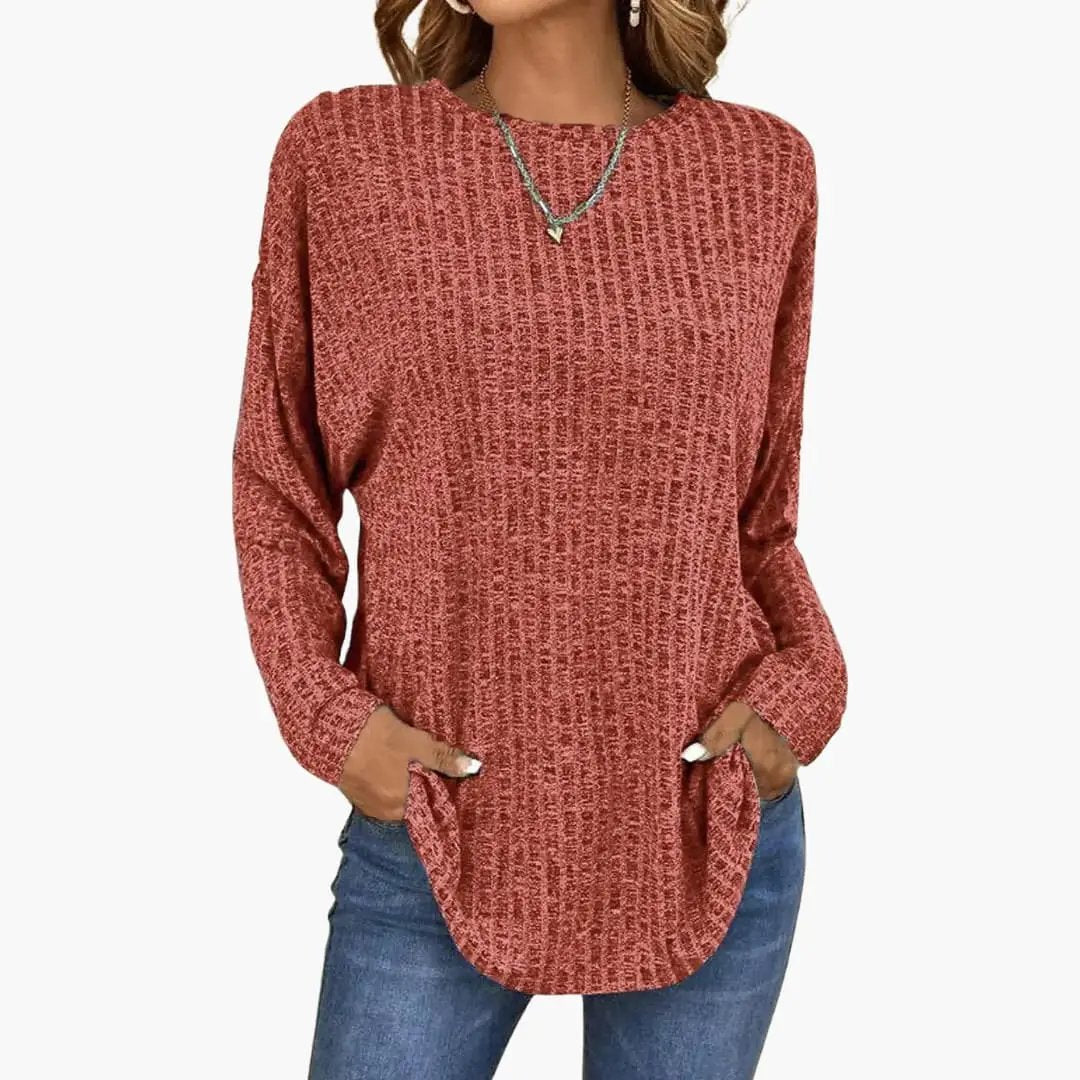 Women's knit sweater with ribbed surface in rust red, round neckline, relaxed fit with front pockets.