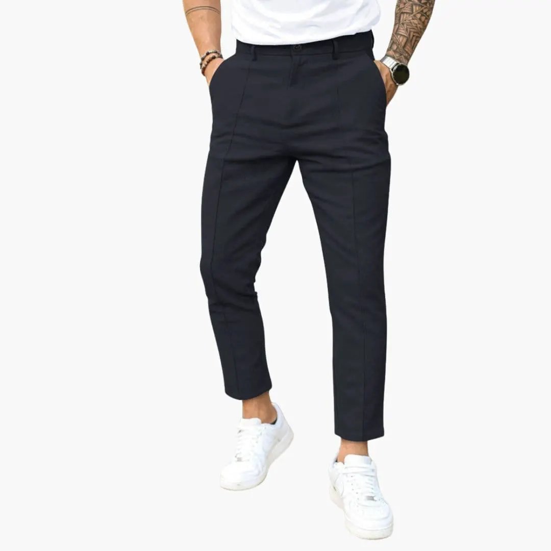 Men's pants with belt loops and straight leg in dark navy, shown with white sneakers.