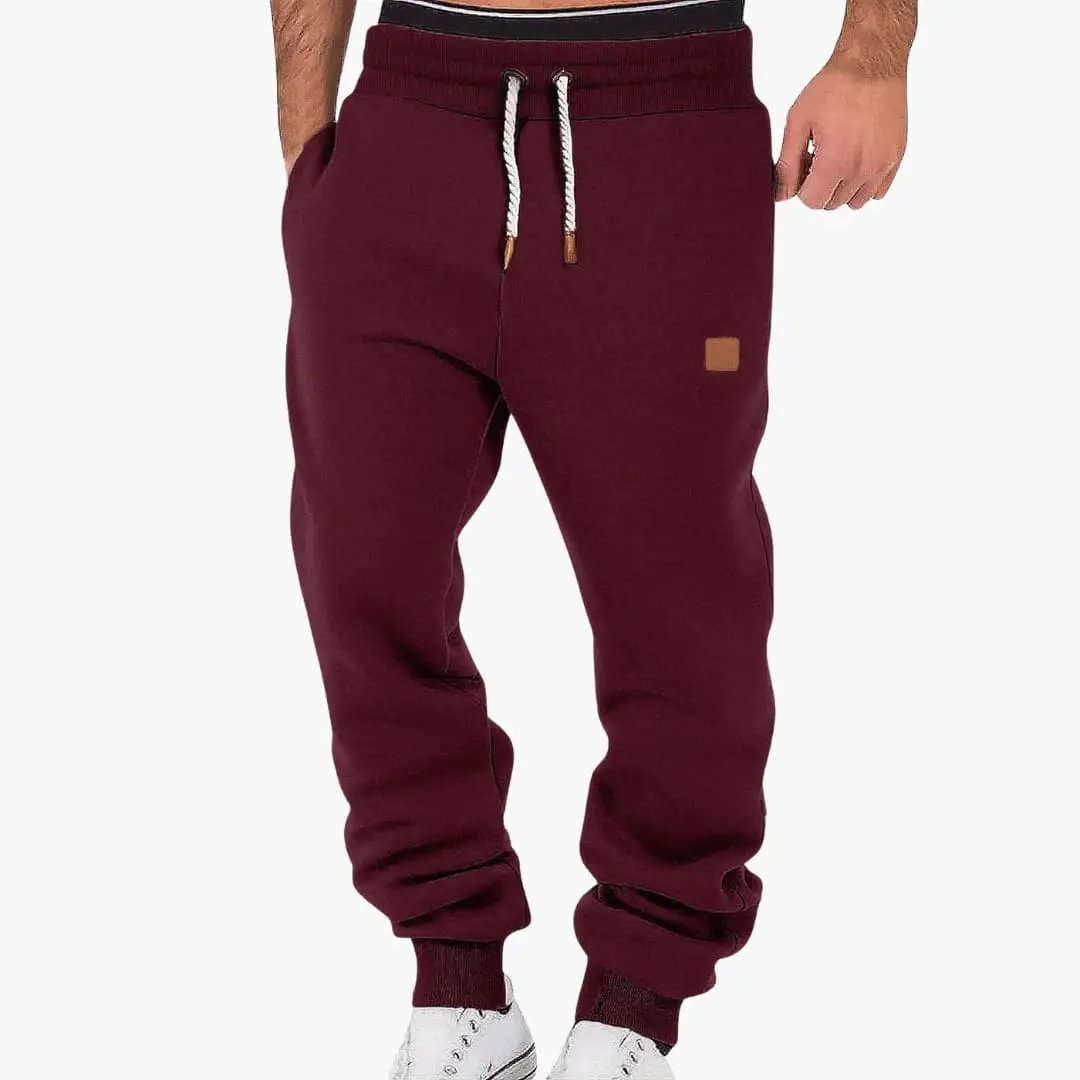 Men's jogging pants with pockets and drawstring waistband, burgundy, cuffed ankles.