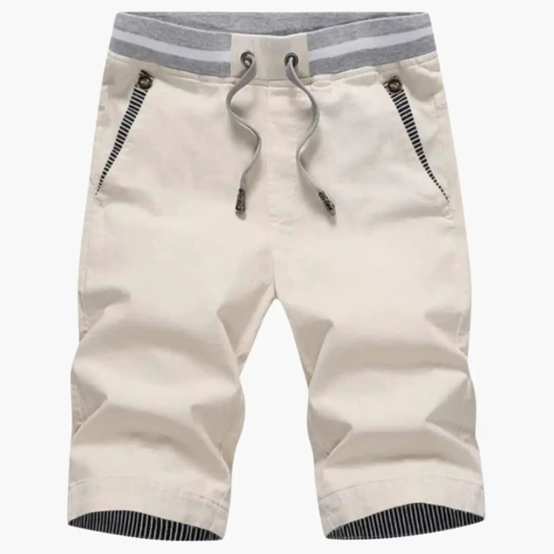 Wilfred Smith men's jogger shorts in beige with elastic waistband, drawstring, turn-up hem, and zip pockets.