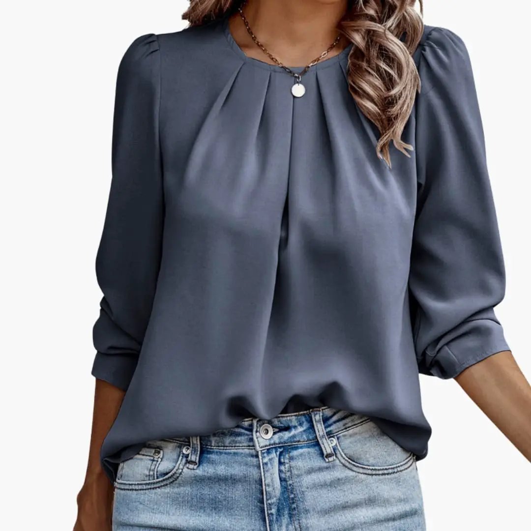 Women’s blue-gray satin blouse with pleated puff sleeves, tucked into denim jeans.