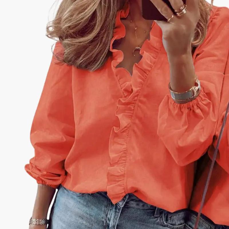 Women's coral blouse with V-neck and ruffle detail, long sleeves with elastic cuffs.