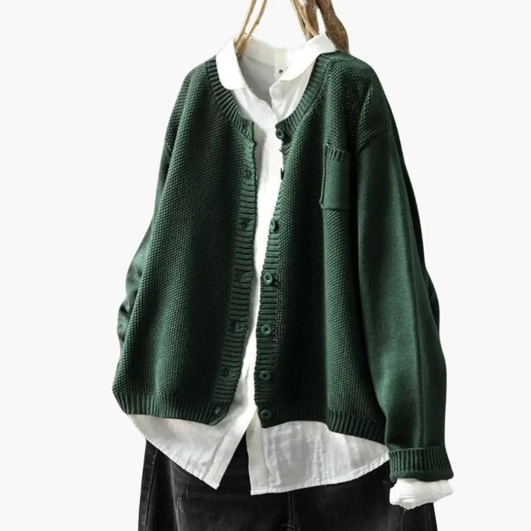 Women's button-up cardigan in dark green textured knit with chest pocket, layered over a white shirt.