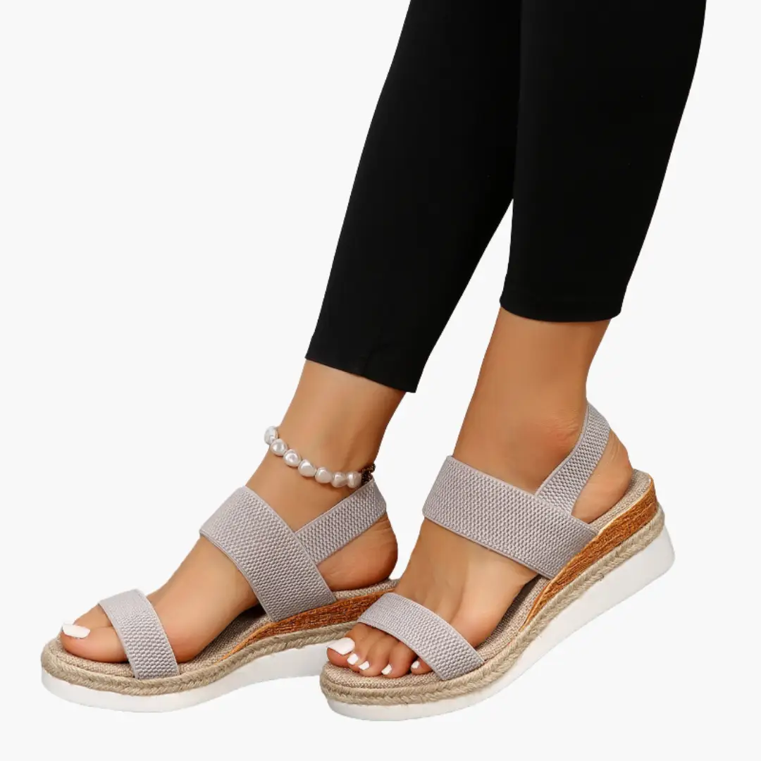 Pair of women's orthopedic sandals with cushioned sole and adjustable light beige woven straps, espadrille-style midsole.