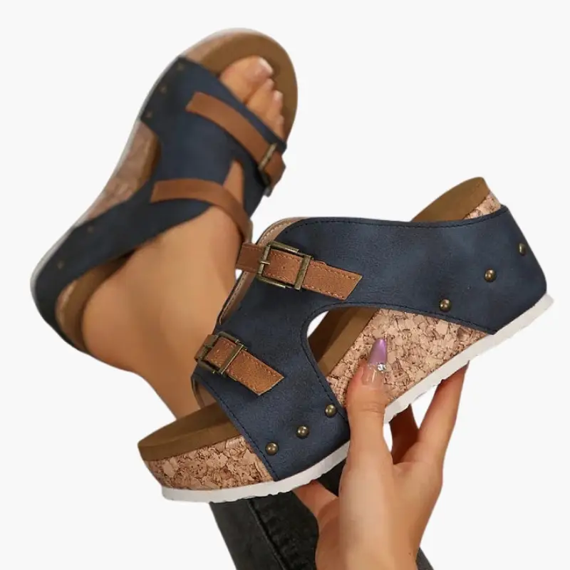 Pair of women’s orthopedic sandals with navy blue straps, cork wedge, and adjustable brown buckles